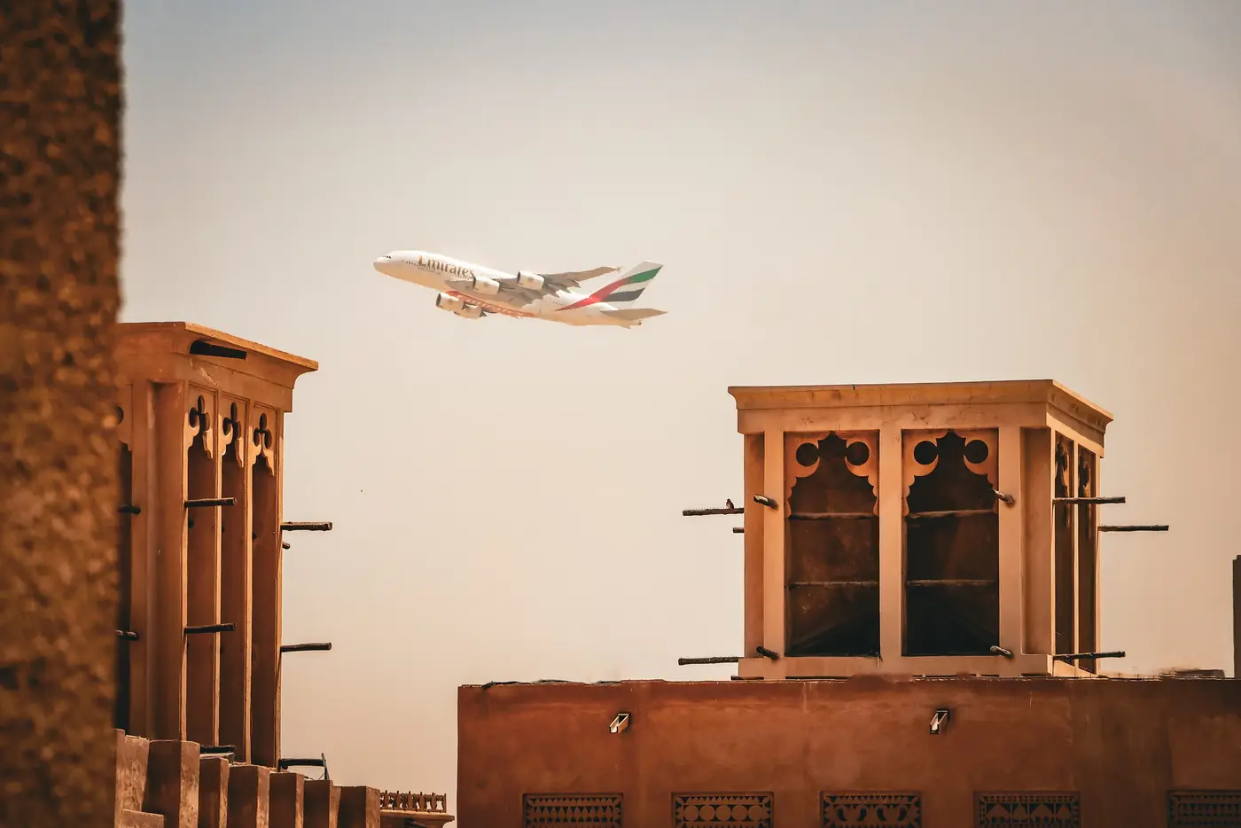 Wind towers in historic Al Fahidi with a passing aircraft