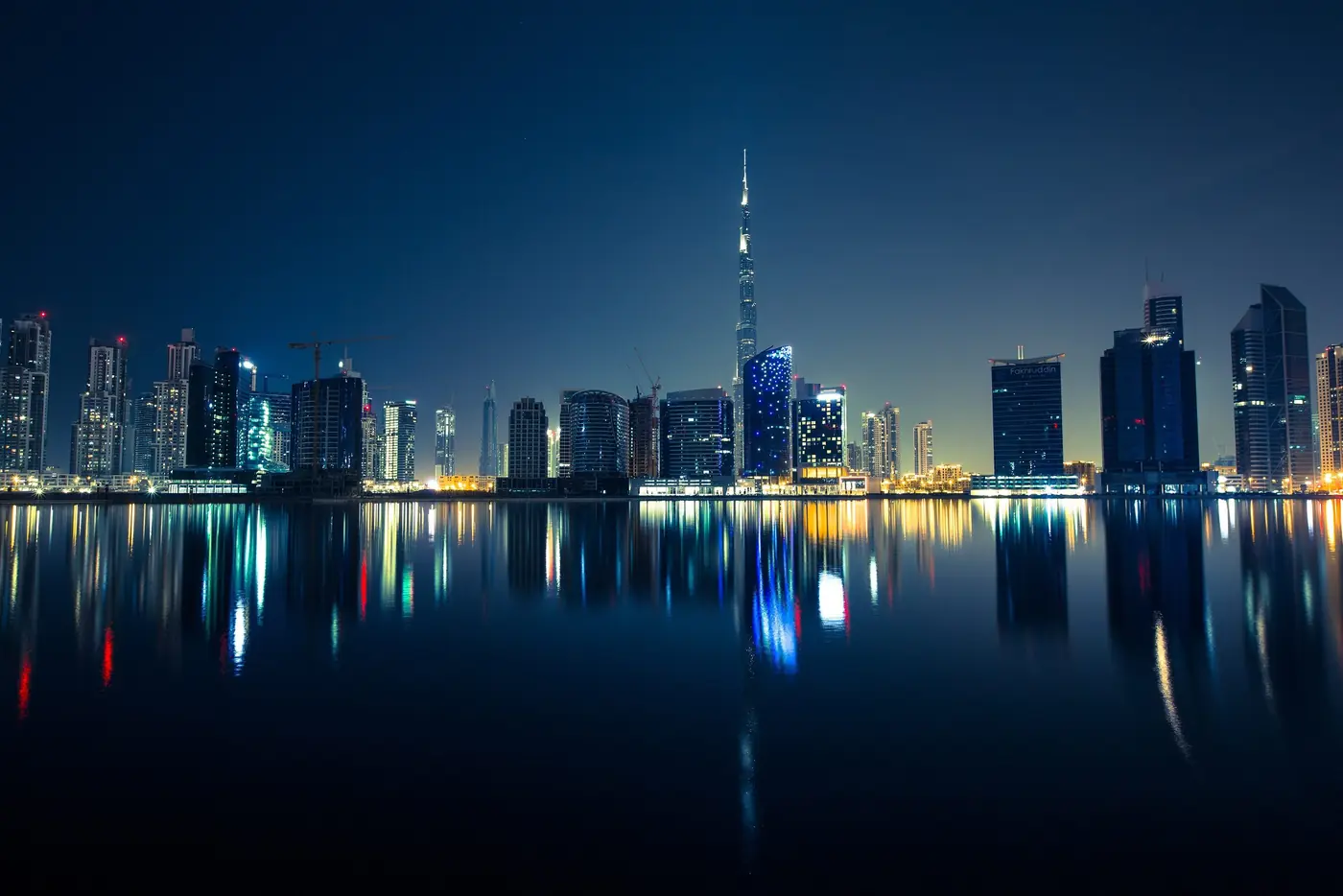 Dubai skyline reflected in still water at night